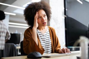 Header Image (Image 2 - woman at desk with hand on head): "Professional woman experiencing hiring a virtual assistant problems while working at office desk
