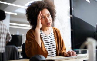 Header Image (Image 2 - woman at desk with hand on head): "Professional woman experiencing hiring a virtual assistant problems while working at office desk