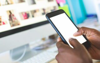 Business leader scrolling Instagram to hire virtual assistant on phone at desk