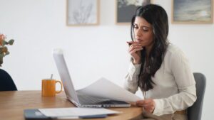 Professional businesswoman identifying virtual assistant red flags while reviewing hiring options at desk