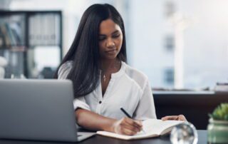 Business leader evaluating where to get a virtual assistant, reviewing information on laptop and taking notes