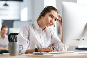 Confused cheap virtual assistant at computer looking stressed and uncertain while working remotely