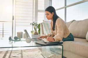 Professional accessing weekend virtual support while working from home office with laptop and planning materials